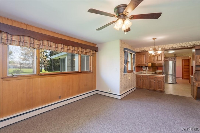 unfurnished living room with carpet flooring, a ceiling fan, a baseboard heating unit, and wallpapered walls