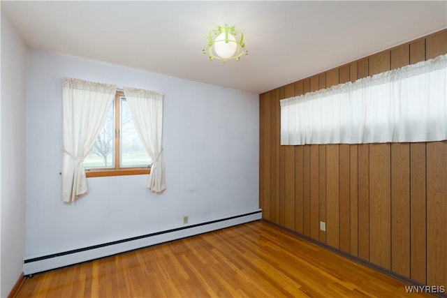 empty room featuring baseboard heating and wood finished floors