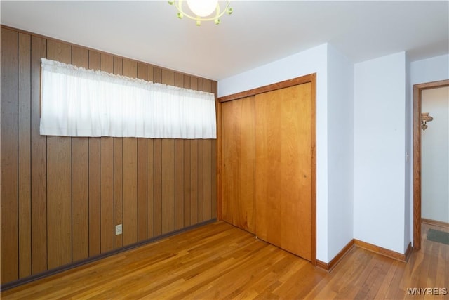 empty room with wooden walls, baseboards, and wood finished floors