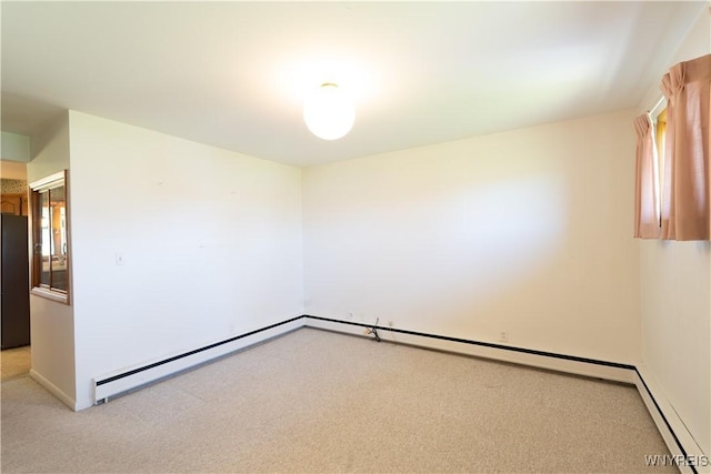 empty room with light colored carpet, a baseboard radiator, and baseboards