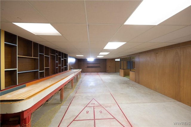 interior space with shuffleboard, wooden walls, and a paneled ceiling