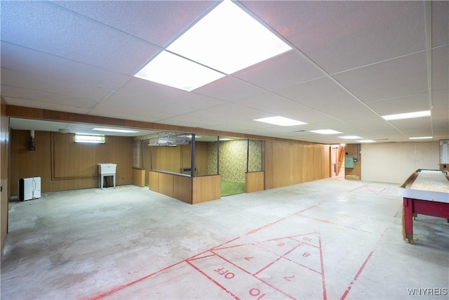 finished basement featuring wood walls and a paneled ceiling