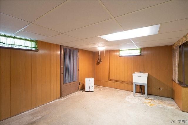 basement featuring wooden walls and a paneled ceiling