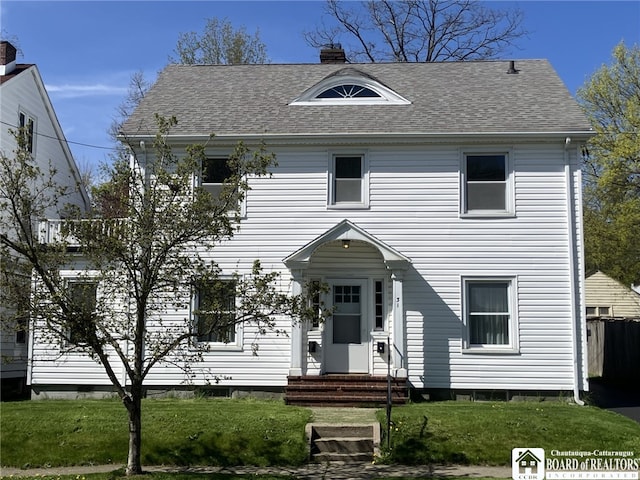 colonial house featuring a front lawn, roof with shingles, a chimney, and entry steps
