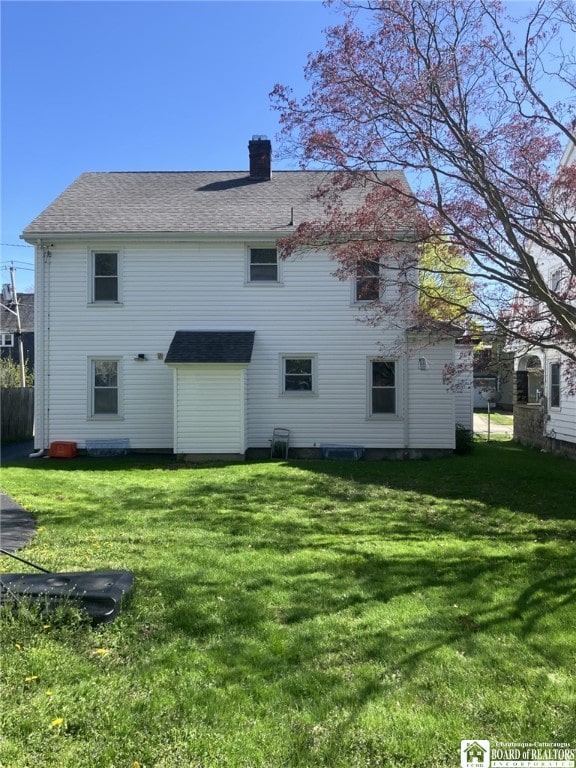 back of house with a lawn and a chimney