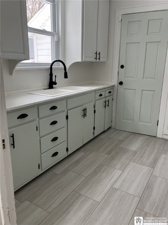 kitchen with a sink, light countertops, and white cabinetry