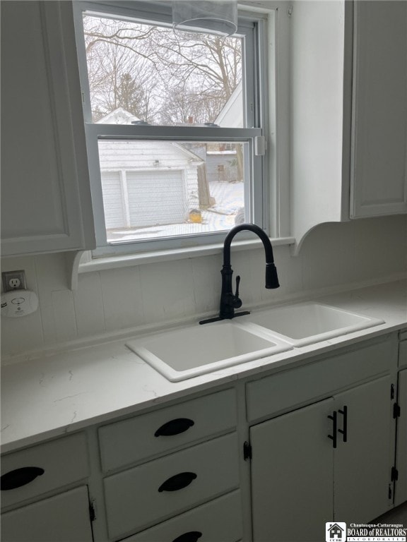 kitchen with a sink, white cabinets, and light countertops
