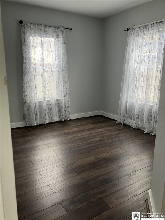 empty room with baseboards and dark wood finished floors
