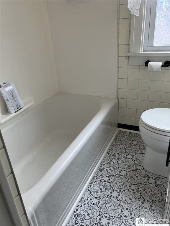 bathroom featuring toilet, tile patterned flooring, and a bath