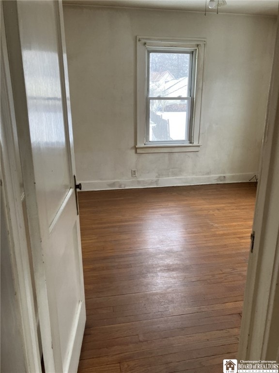unfurnished room with wood-type flooring and baseboards
