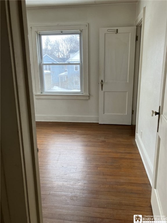 spare room with baseboards and hardwood / wood-style flooring