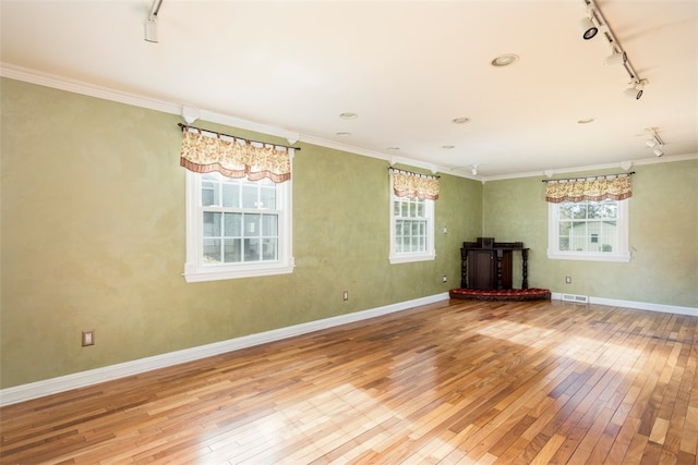 unfurnished living room featuring plenty of natural light, rail lighting, visible vents, and hardwood / wood-style flooring