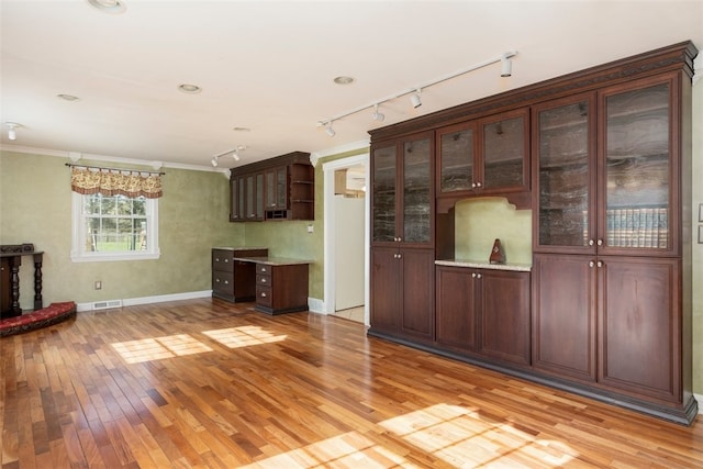 unfurnished living room featuring visible vents, light wood-type flooring, rail lighting, baseboards, and ornamental molding