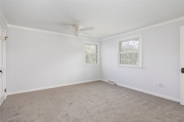 carpeted empty room featuring crown molding, a ceiling fan, baseboards, and visible vents