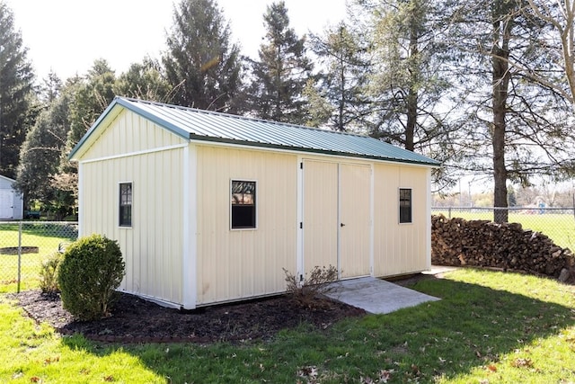 view of outdoor structure featuring fence and an outbuilding