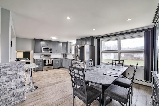 22 Plaza Dr, Amherst, NY 14221 - dining space with a baseboard heating unit, a healthy amount of sunlight, and light wood-style floors