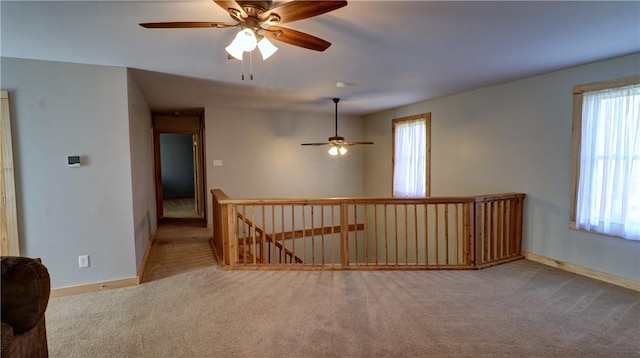 empty room with plenty of natural light, ceiling fan, and carpet flooring