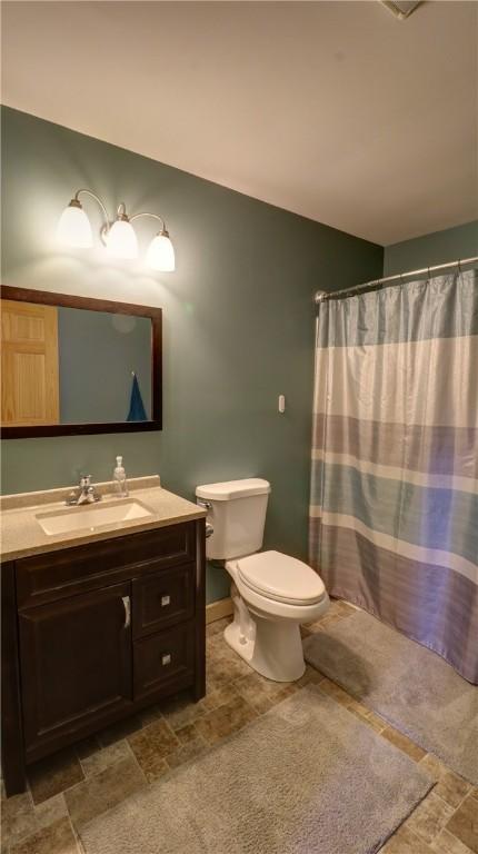 bathroom featuring vanity, toilet, and curtained shower