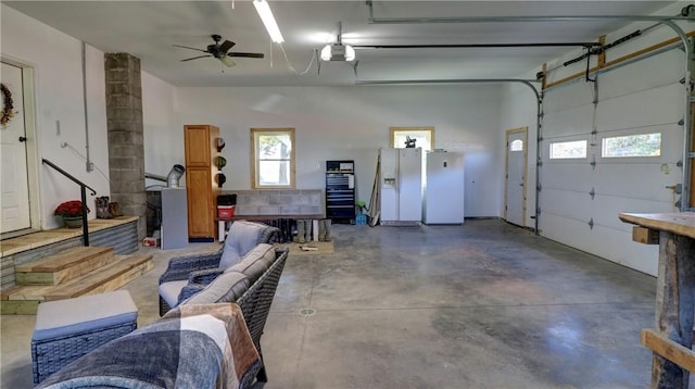 garage with a garage door opener, white refrigerator with ice dispenser, ceiling fan, and freestanding refrigerator