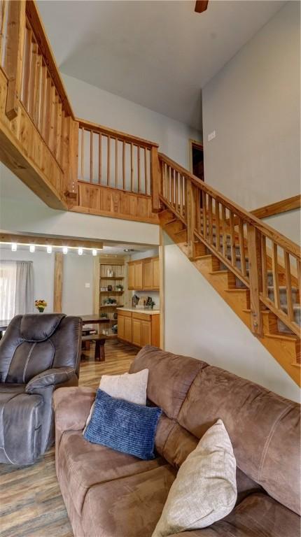 living area featuring a ceiling fan, light wood-style flooring, and stairway