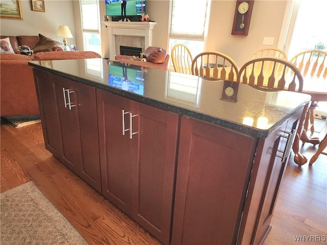 5260 Murphy Rd, Orchard Park, NY 14127 - kitchen with open floor plan, a tile fireplace, dark stone countertops, and light wood-type flooring
