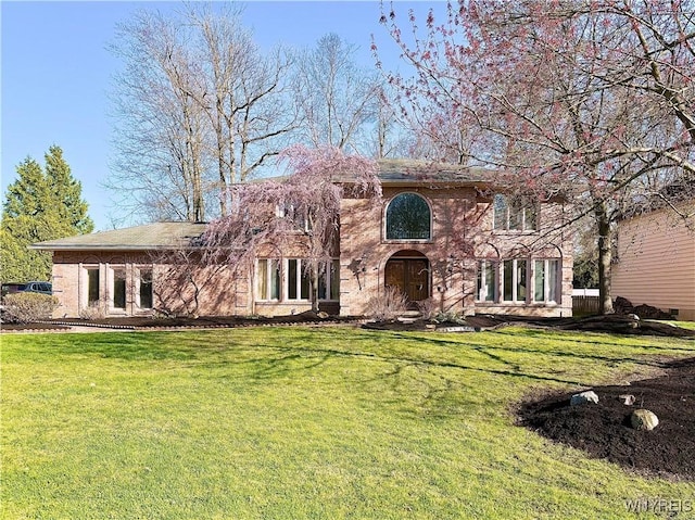 view of front facade with brick siding and a front yard