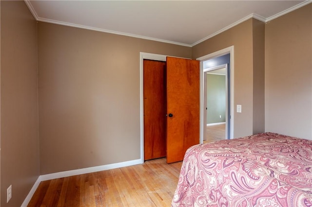 bedroom featuring crown molding, baseboards, light wood-style flooring, and a closet