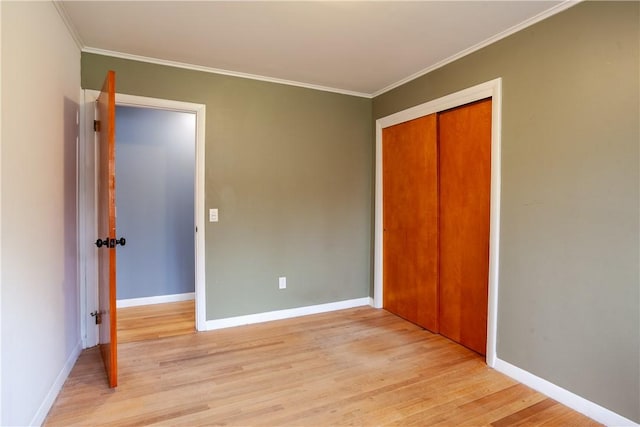 unfurnished bedroom featuring light wood-type flooring, ornamental molding, baseboards, and a closet