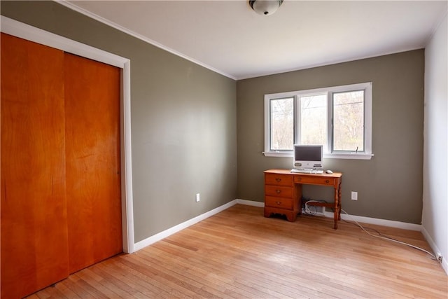 home office featuring light wood-style floors, ornamental molding, and baseboards