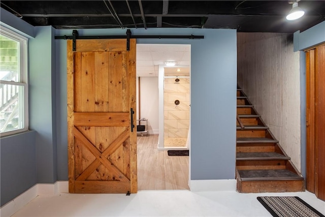 basement featuring stairs, a barn door, and wood finished floors
