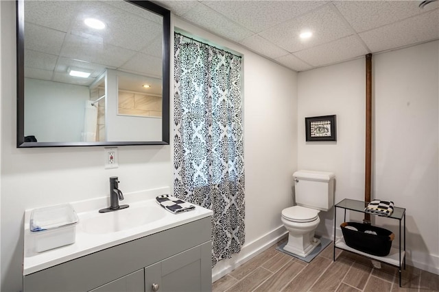 bathroom featuring toilet, recessed lighting, a drop ceiling, and vanity