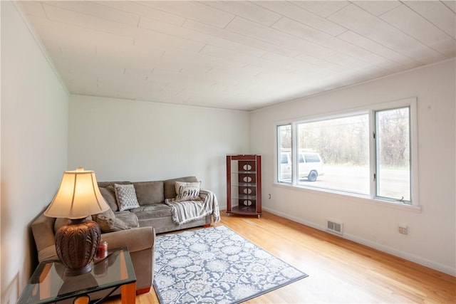 living area with baseboards, visible vents, and light wood-style floors