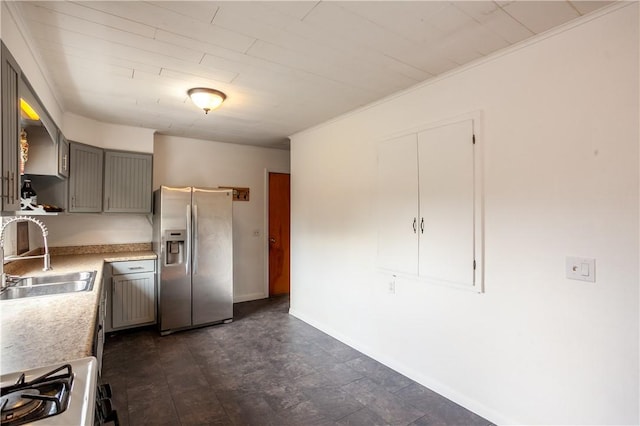 kitchen featuring range with gas stovetop, light countertops, gray cabinets, stainless steel fridge with ice dispenser, and a sink