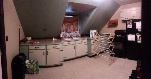 kitchen featuring vaulted ceiling and white cabinetry