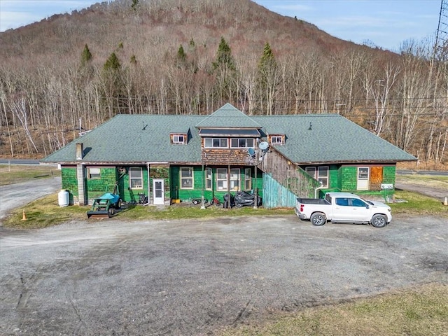 townhome / multi-family property with stairs, a shingled roof, and a mountain view