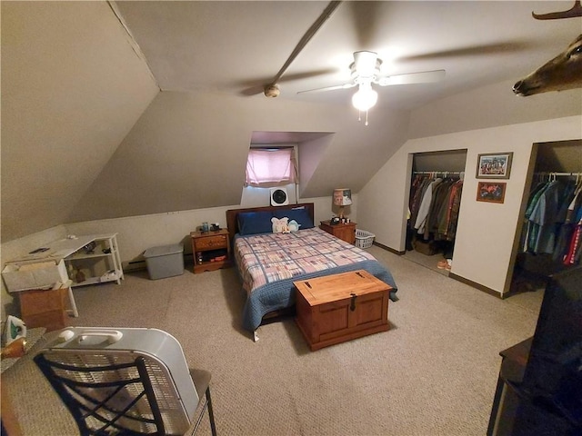 carpeted bedroom with two closets, a ceiling fan, baseboards, and vaulted ceiling