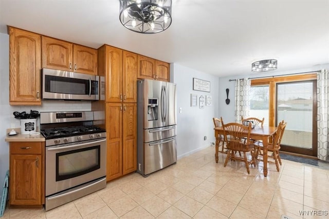 kitchen with light tile patterned floors, appliances with stainless steel finishes, and brown cabinetry