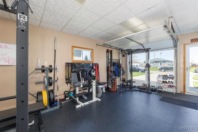 gym featuring a garage, a paneled ceiling, and a wealth of natural light