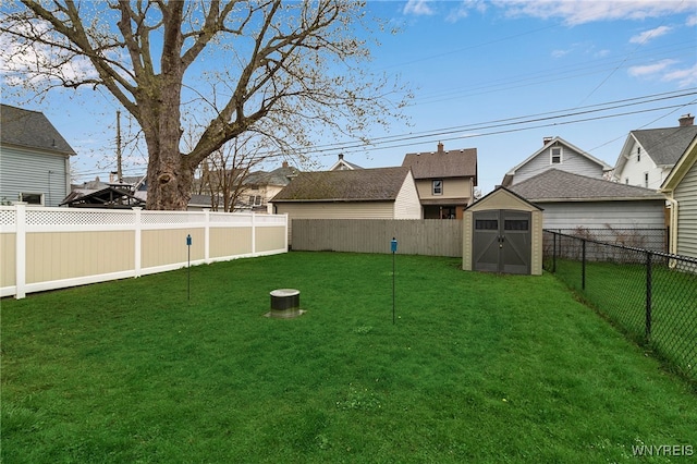 view of yard with an outdoor structure, a fenced backyard, and a storage unit