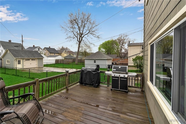 wooden terrace featuring grilling area, a lawn, a residential view, and a detached garage