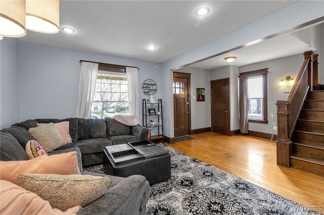 living area featuring stairway, baseboards, light wood-style floors, and recessed lighting