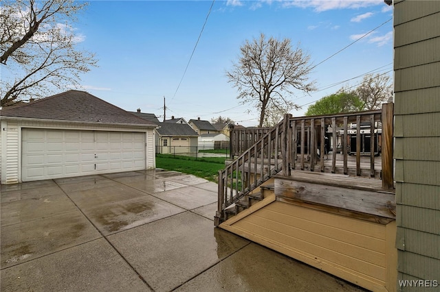 view of patio featuring a detached garage, a deck, fence, and an outdoor structure