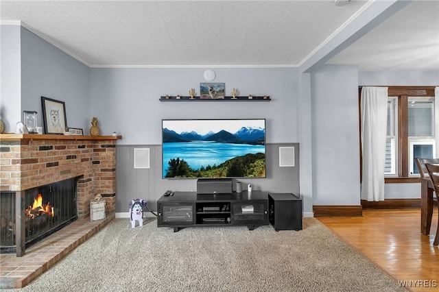 living room with crown molding, carpet floors, a fireplace, and wood finished floors