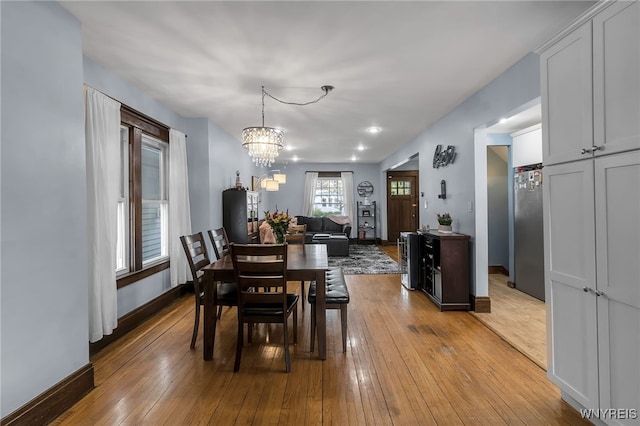 dining area featuring baseboards, light wood-style flooring, and a notable chandelier
