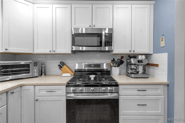 kitchen featuring stainless steel appliances, a toaster, white cabinetry, and tasteful backsplash