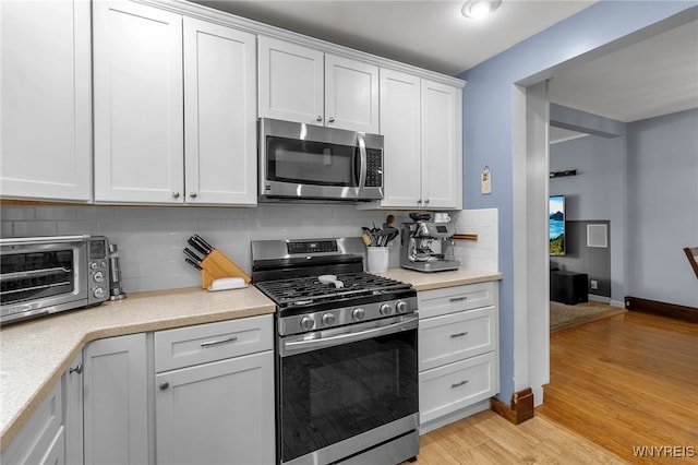 kitchen featuring light countertops, appliances with stainless steel finishes, a toaster, and tasteful backsplash