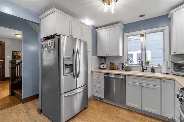kitchen featuring a sink, appliances with stainless steel finishes, light wood-style floors, and light countertops