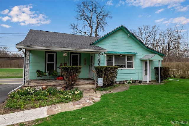 view of front facade with a porch, a shingled roof, and a front yard