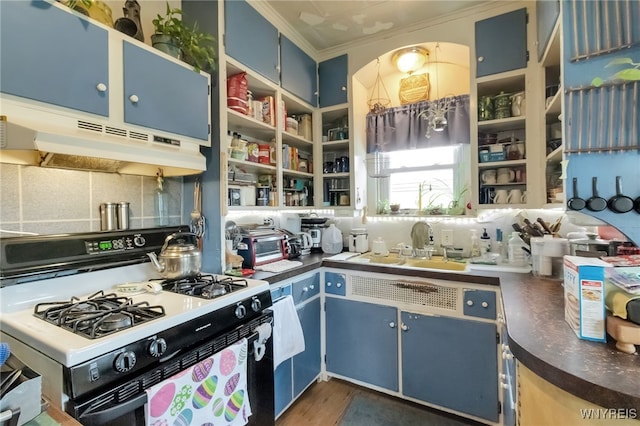 kitchen with blue cabinetry, dark countertops, ornamental molding, range with gas stovetop, and under cabinet range hood