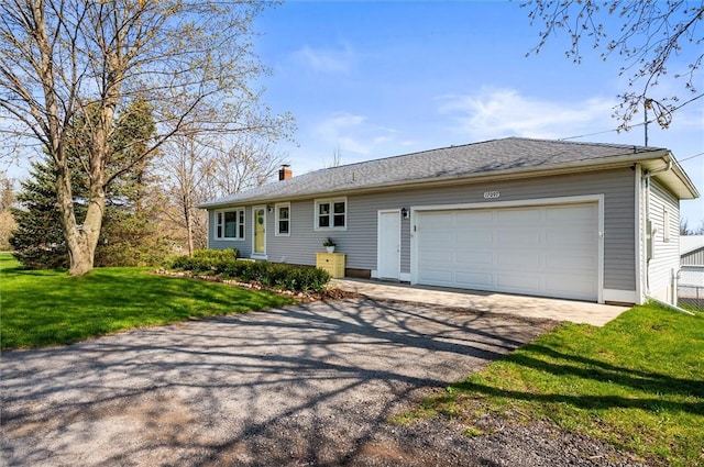 ranch-style house featuring an attached garage, aphalt driveway, a chimney, and a front lawn